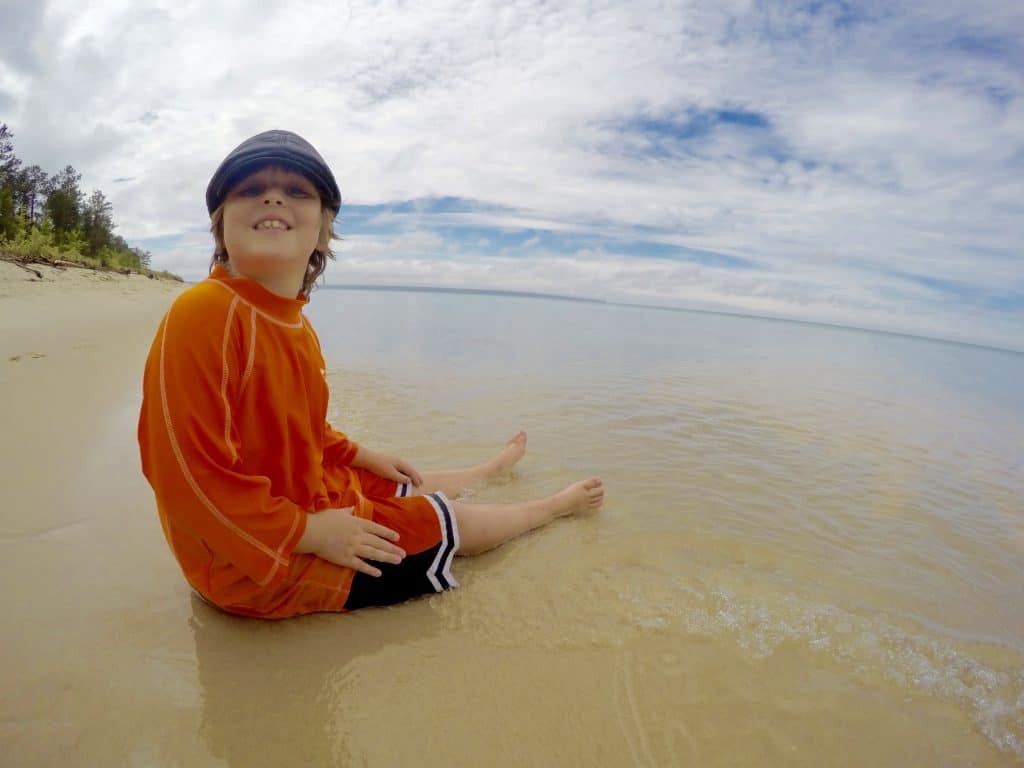 boy sitting on Miner's Beach in Michigan on Lake Superior